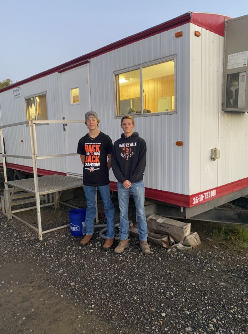 two boys in front of a work trailer